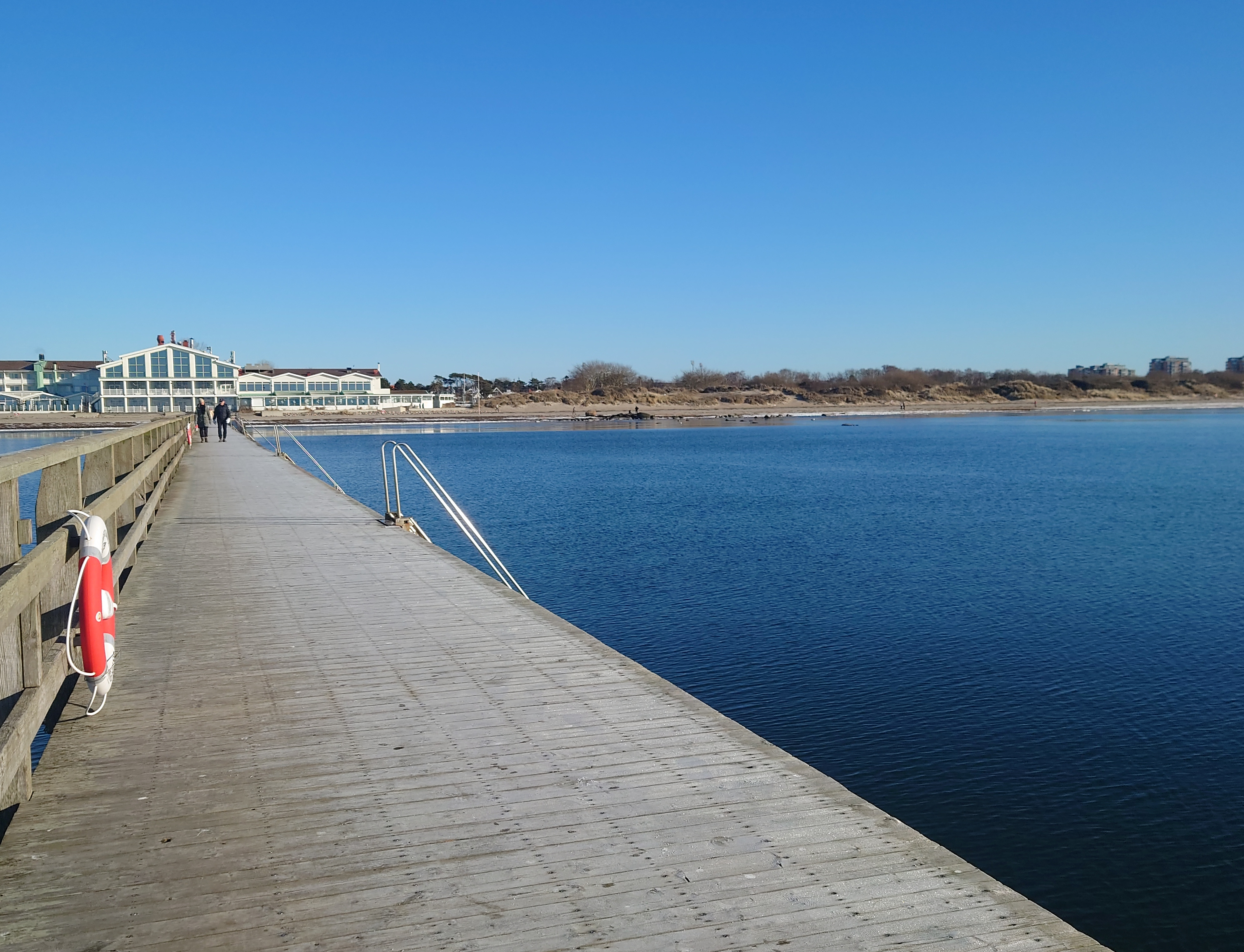 Brygga ut i havet med hotell i bakgrunden