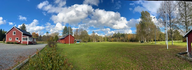 Röd klubbstuga och en stor appellplan. 