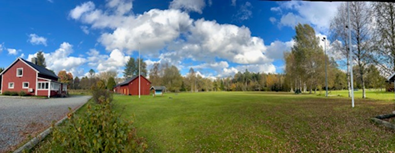 Röd klubbstuga och en stor appellplan.