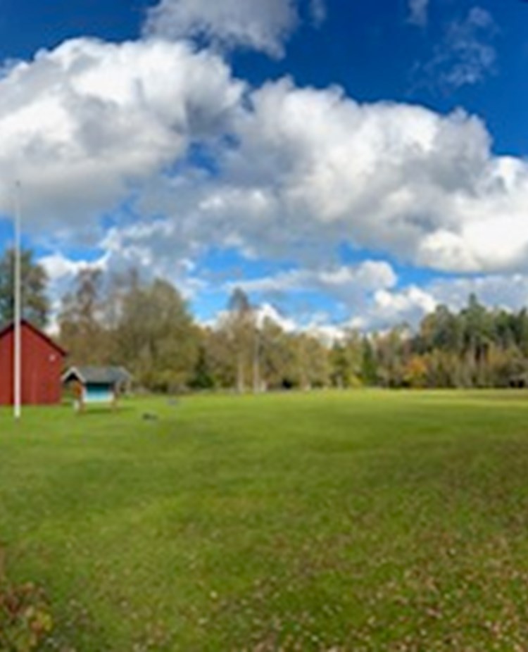 Röd klubbstuga och en stor appellplan.