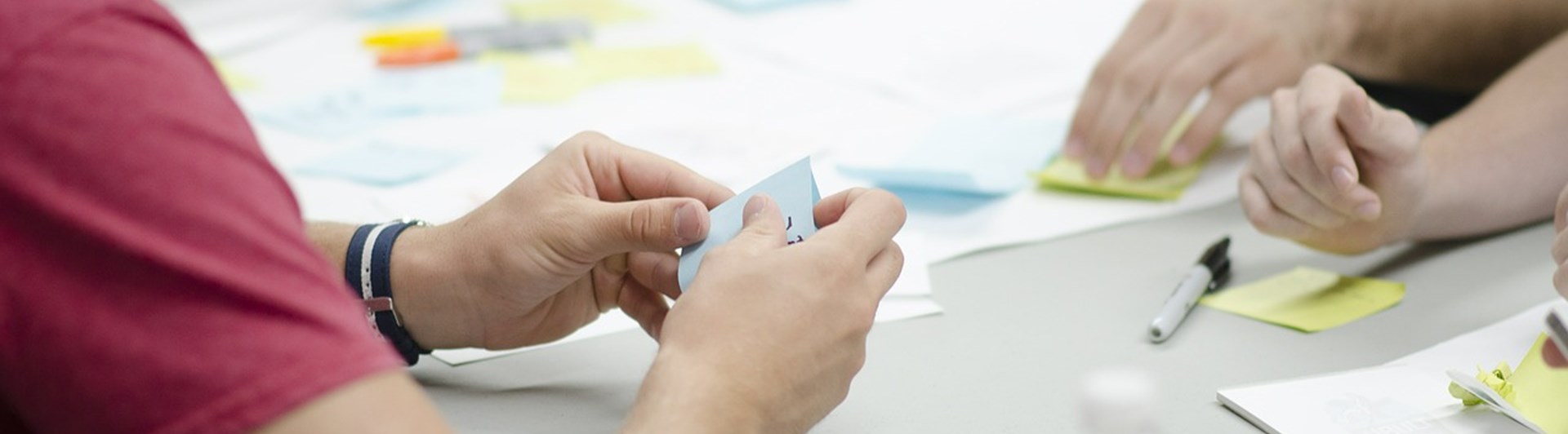 Människor som sitter vid ett bord med anteckningsböcker, pennor och post-it lappar