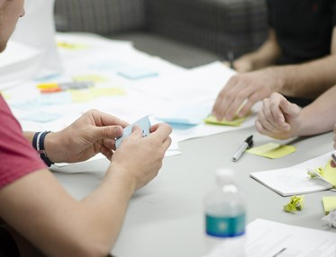 Människor som sitter vid ett bord med anteckningsböcker, pennor och post-it lappar