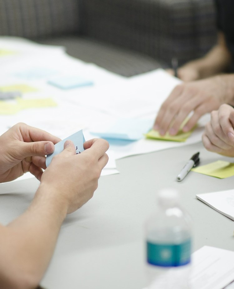 Människor som sitter vid ett bord med anteckningsböcker, pennor och post-it lappar