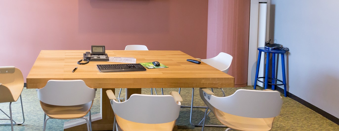 Bild på mindre konferensrum med bord och stolar.