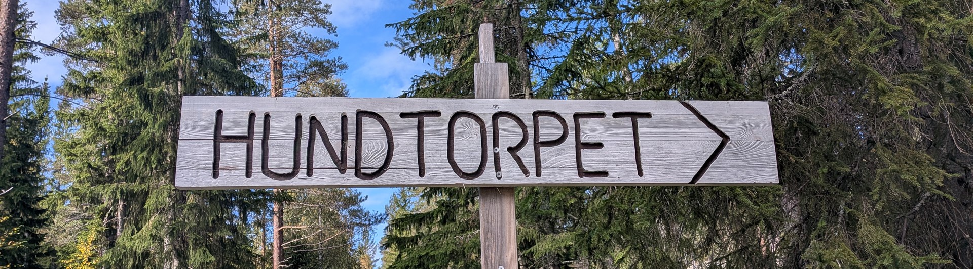 Skylt i trä med texten Hundtorpet och en pil.