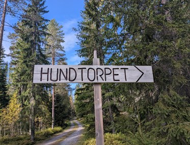 Skylt i trä med texten Hundtorpet och en pil.