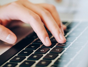 Bild som visar en hand på en bärbar dator.