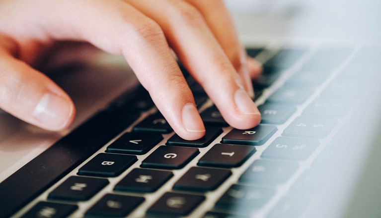 Bild som visar en hand på en bärbar dator.