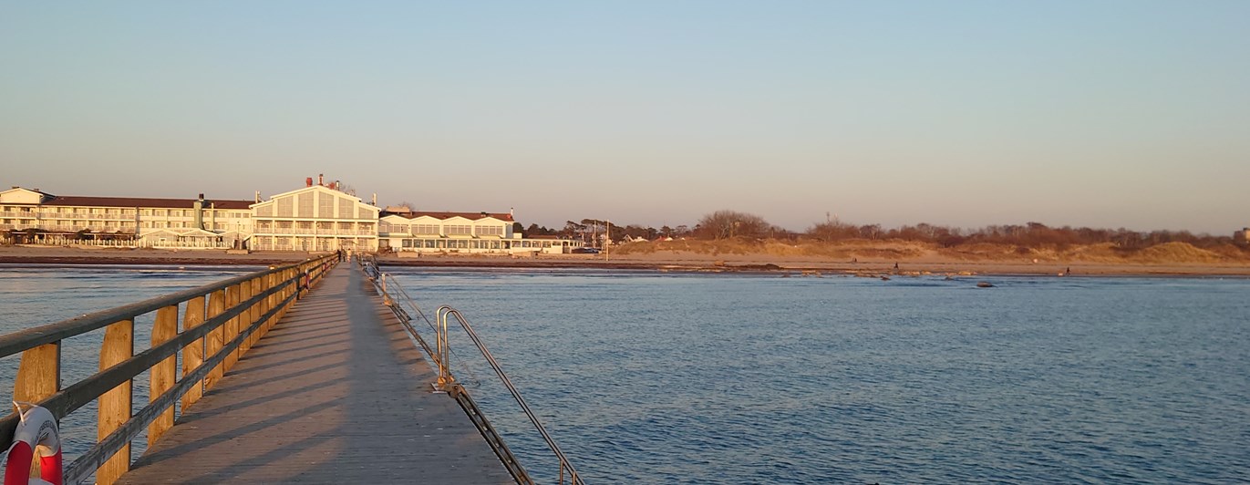 Brygga ut i havet med hotell i bakgrunden