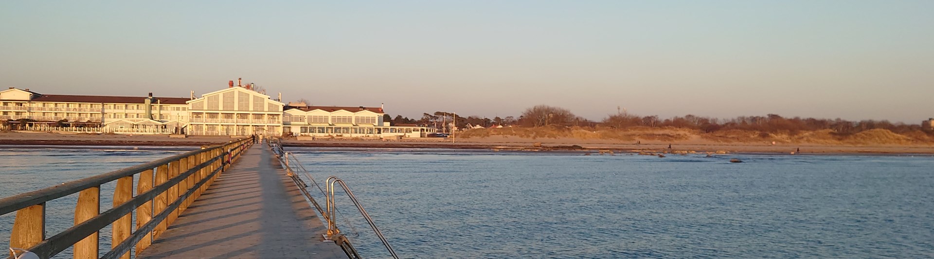 Brygga ut i havet med hotell i bakgrunden