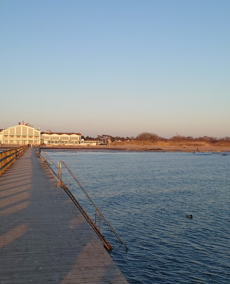 Brygga ut i havet med hotell i bakgrunden